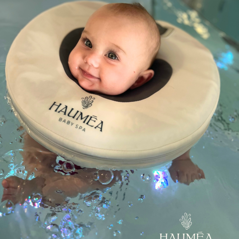 Souris bébé dans une baignoire d'eau avec un collerette de spa pour bébé au logo Hauméa Baby Spa, ambiance relaxante et ludique.