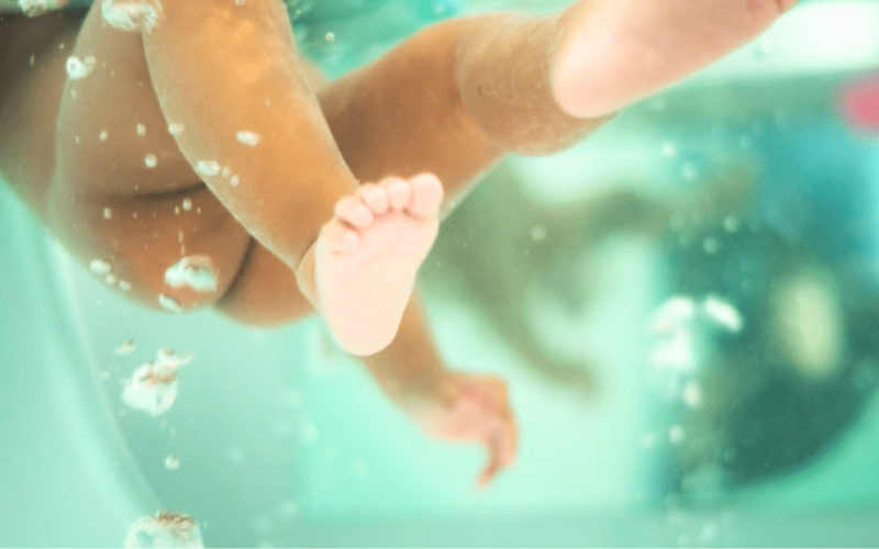 Bébé nageant dans une baignoire de spa pour bébés avec eaux relaxantes et sécurité optimale.