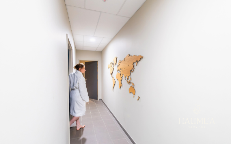 Voyageur bébé dans un spa bébé, décorée avec un globe terrestre en bois sur un mur blanc, intérieur moderne et apaisant, ambiance détente pour soins de bébés.