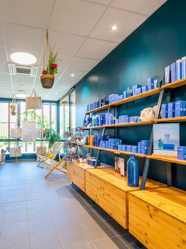 Apaisant espace de boutique avec étagères en bois et produits de soins pour bébés à Hauméa Baby Spa, ambiance chaleureuse, végétation et décoration intérieure en bleu pour une expérience détente.