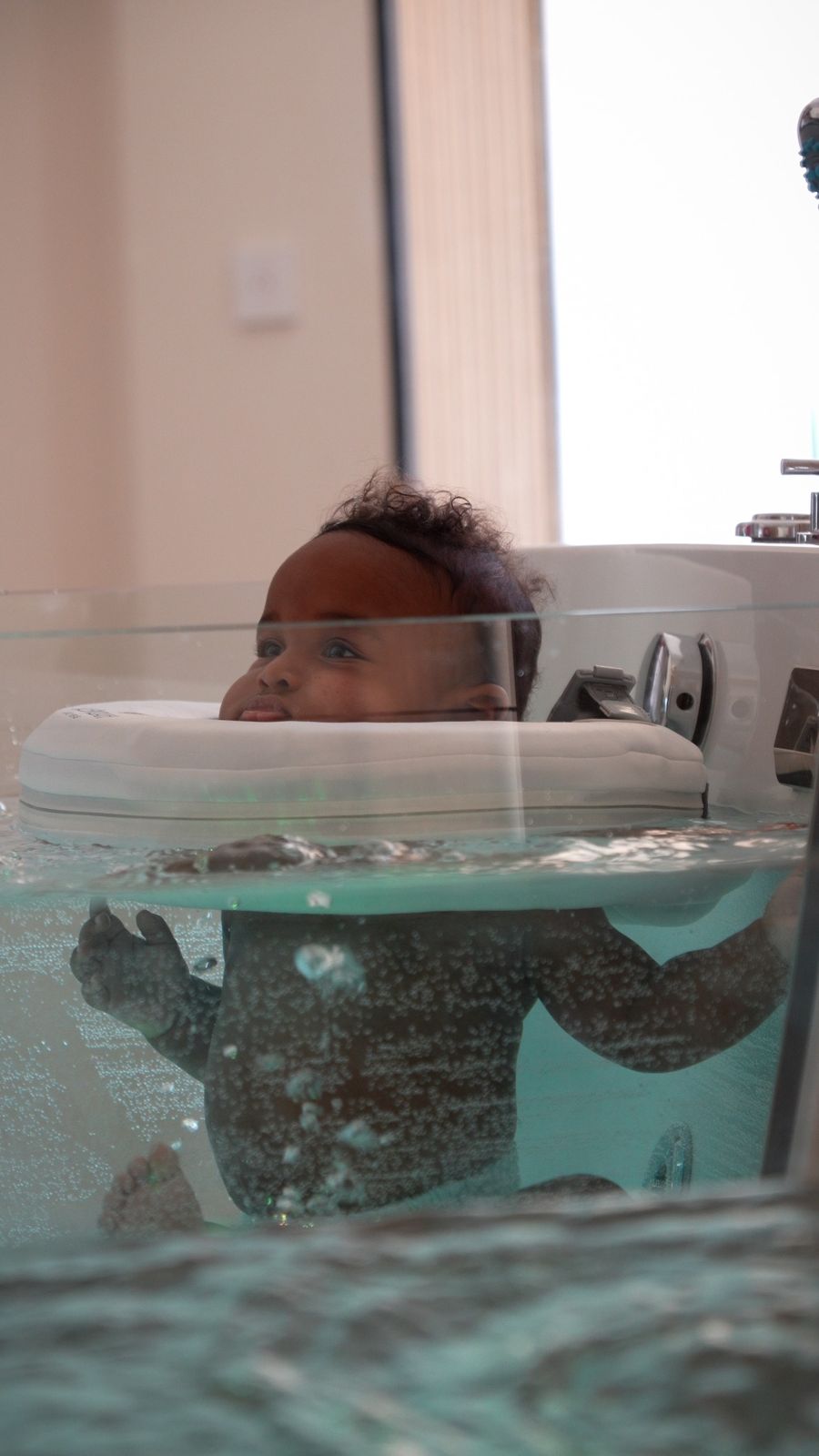 Un bébé flotte dans le bain d'hydrothérapie du Baby Spa Hauméa